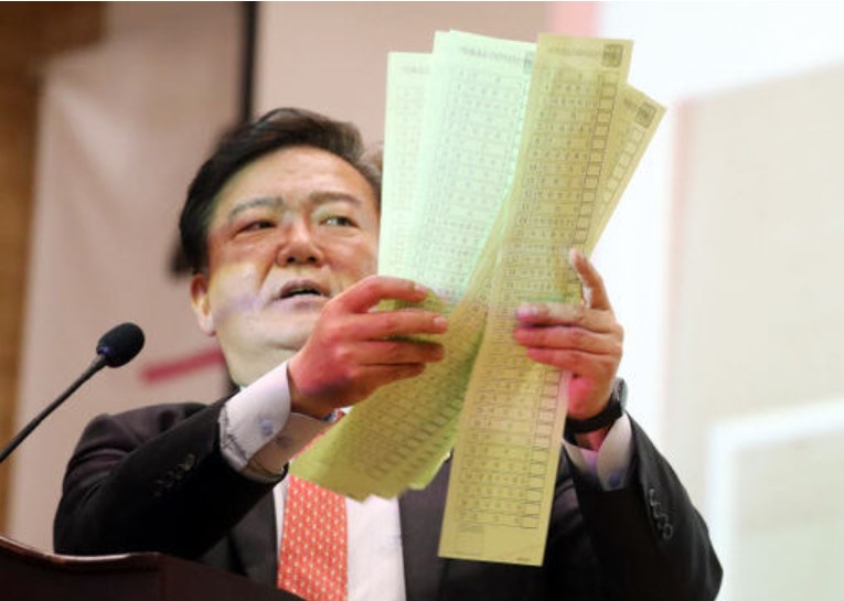 민경욱 前 의원이 투표관리관 날인이 없는 당일 비례투표용지를 펼쳐 보이고 있다.